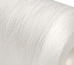 Close-up of white textured fabric on a roll, showing a fibrous surface and curved edge.