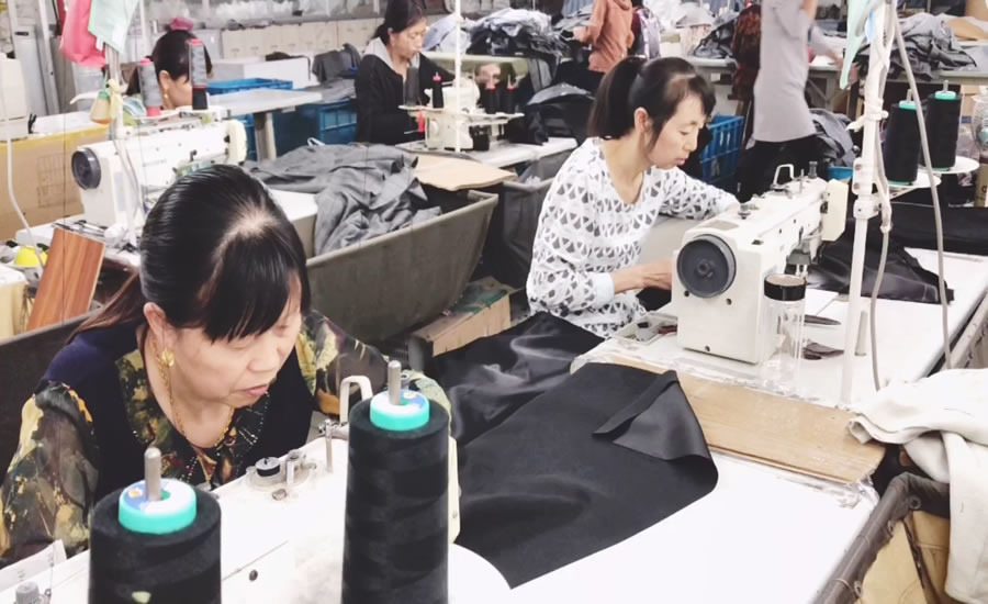Clothing factory workers use sewing machines