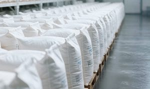 Row upon row of white bags on wooden pallets in a clean warehouse aisle, organized for storage or shipment.