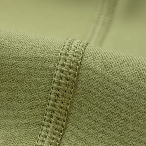 Close-up of green fabric with a stitched seam running diagonally across the image.