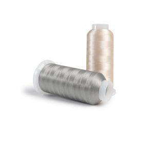 Two spools of sewing thread, one silver and one beige, on a white background.