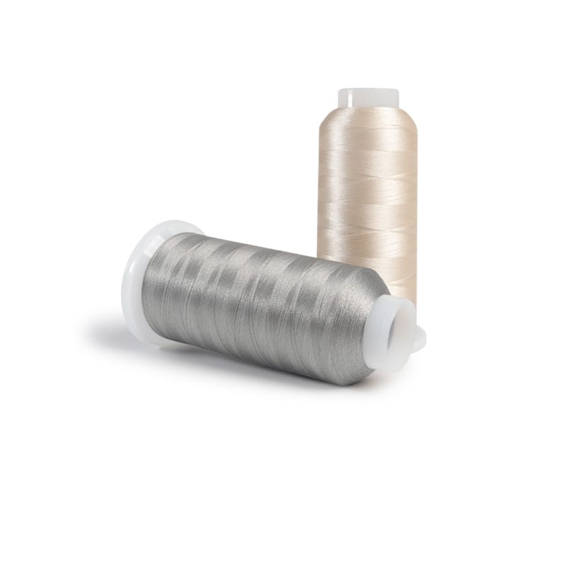Two spools of sewing thread, one silver and one beige, on a white background.