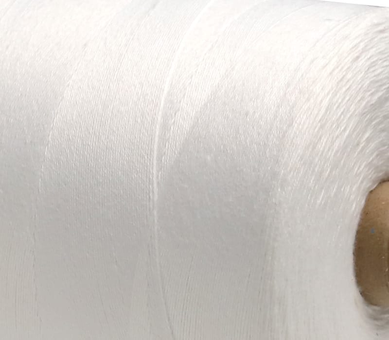 Close-up of white fabric showing fine weave and a brown circular button-like detail on the edge.