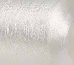 Close-up of a brushed silver metal surface with a partial beige circular object on the right.