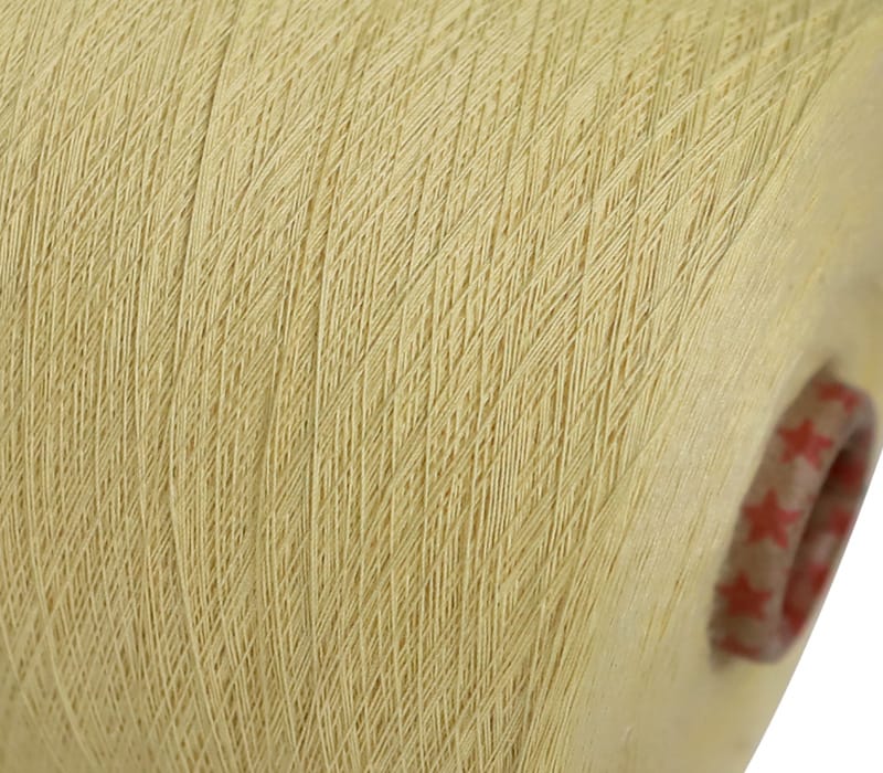 Close-up of pale yellow thread wound on a spool, with a small red-star patterned button visible on the edge.