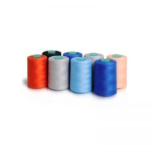 Row of colorful sewing thread spools on a white reflective surface