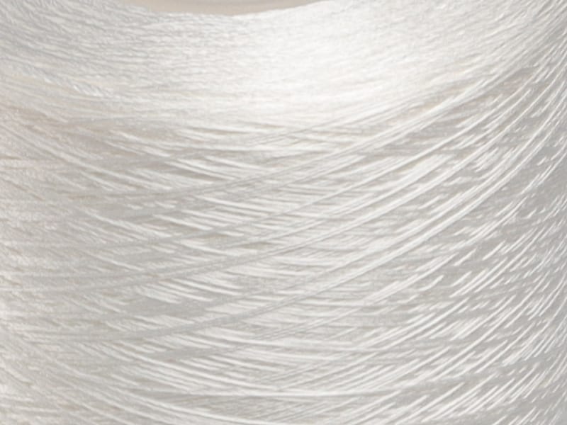 Close-up of white fabric with visible fiber texture and swirling thread patterns