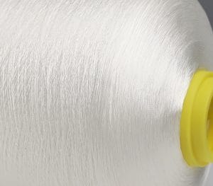 Close-up of white thread wound around a yellow spool core, showing detailed fibers in a textile setup.
