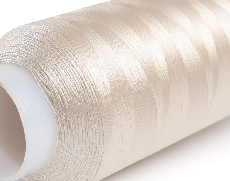 Roll of metallic beige sewing thread on a white spool