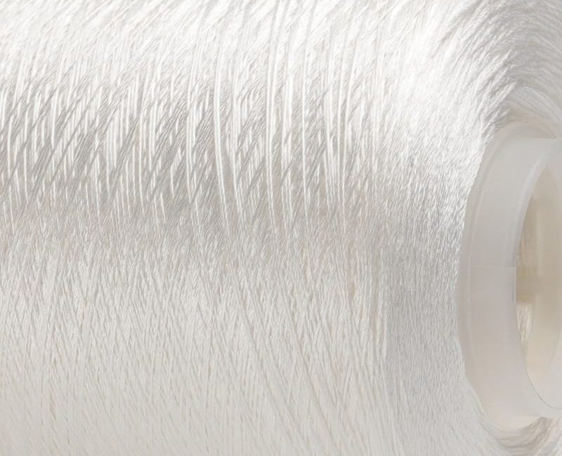 Close-up of white thread tightly wound around a plastic spool.