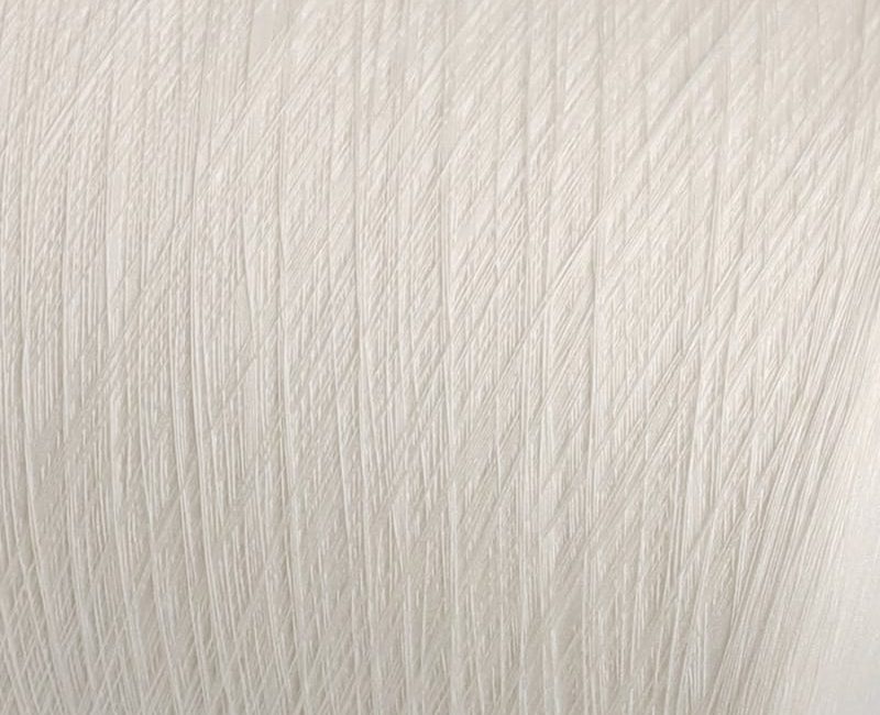 Close-up of a pale textured surface with numerous diagonal scratches or grooves throughout.